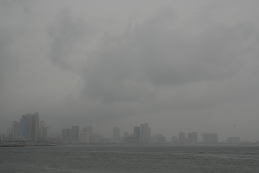 Heavy rain and clouds seen above the grey Manila skyline as Typhoon Noru approaches.