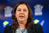 Ms Palaszczuk speaks at a press conference in front of a blue screen with the Queensland government logo.