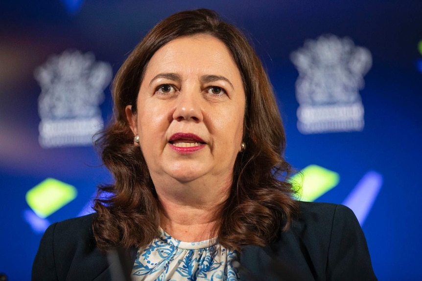 Ms Palaszczuk speaks at a press conference in front of a blue screen with the Queensland government logo.