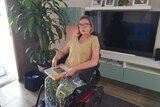 a woman in a wheelchair looking into the camera from her living room