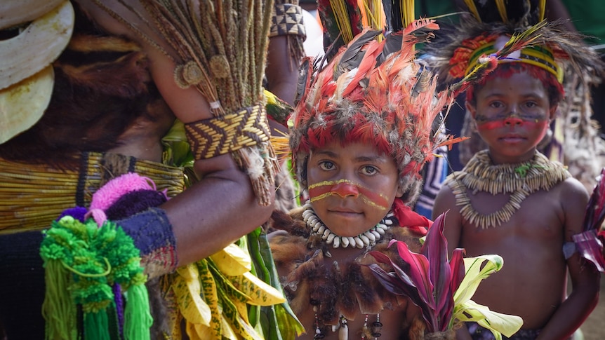 Two children stand wearing traditional PNG dress