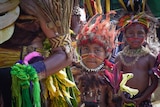 Two children stand wearing traditional PNG dress