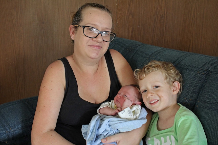 Karli Phillips sits on a sofa with her four year old son and four day old son.
