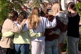 a group of young women hug and pay tribute outside the house where two women were killed at floreat in wa