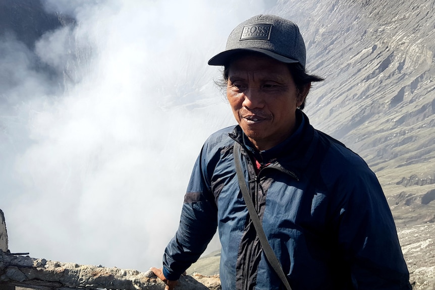 A man stands on the edge of a smouldering volcano.