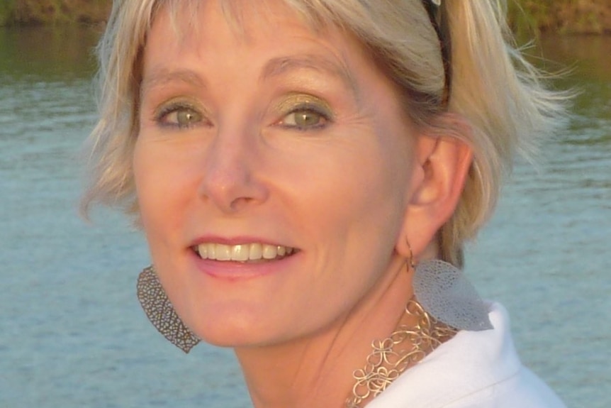 A headshot of Sue Coffee with water in the background.