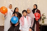 A group photos of siblings with balloons and light decorations at the background