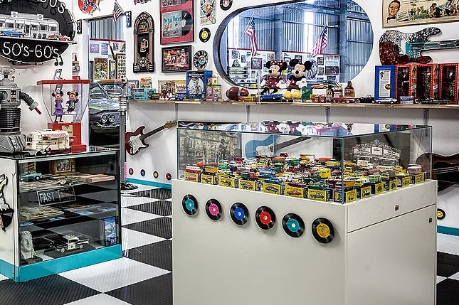 A collection of 1950s era cars and toys behind glass in a museum.