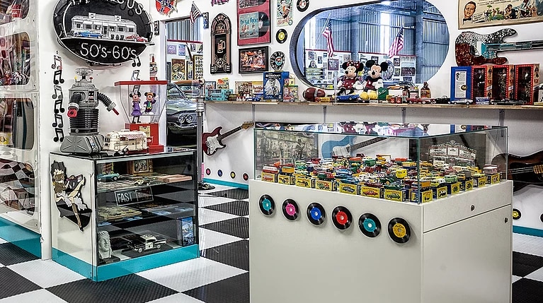 A collection of 1950s era cars and toys behind glass in a museum.