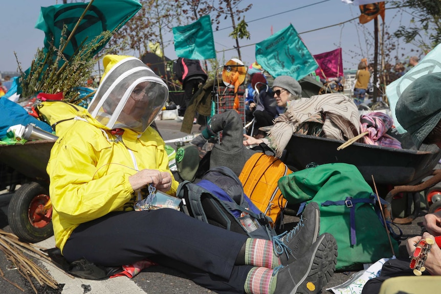 A climate change demonstrator knits while sitting in the road in London.