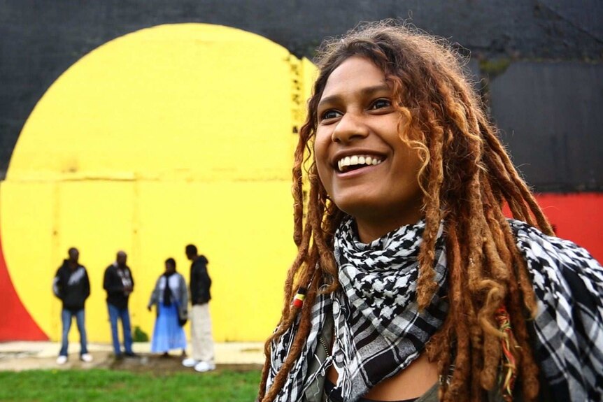 Alice Eather with the Aboriginal flag mural
