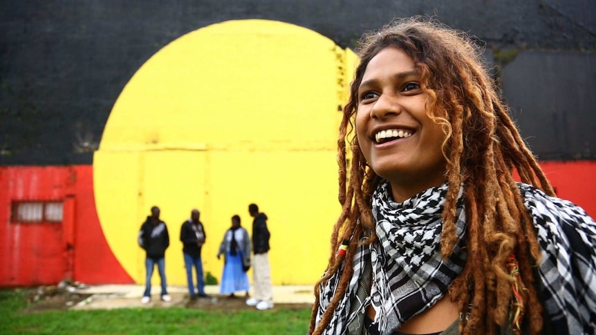 Alice Eather with the Aboriginal flag mural