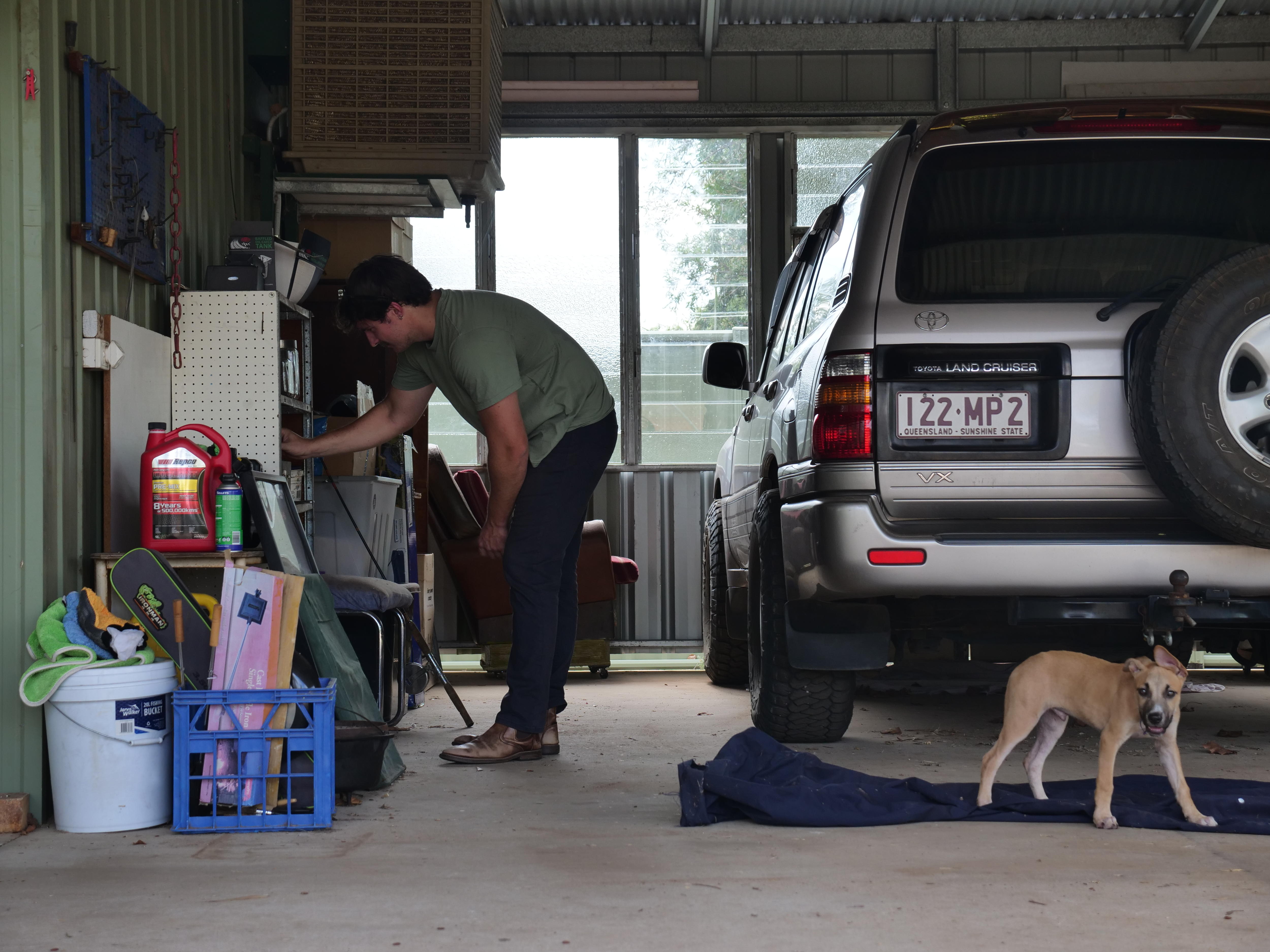 Hombre en el cobertizo al lado del auto