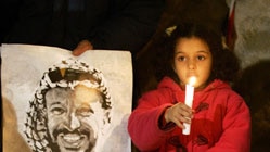 A girl holds a candle in support of Yasser Arafat.