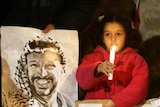 A girl holds a candle in support of Yasser Arafat.