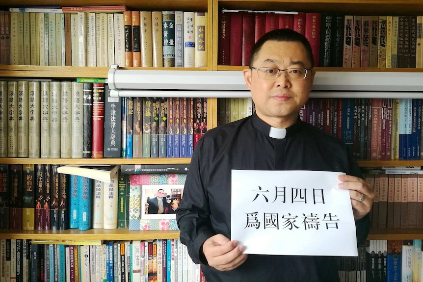 Paster Wang Yi standing in front of the book shelf.