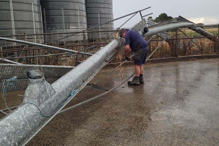 A farmer fixes damaged metal at his silo.