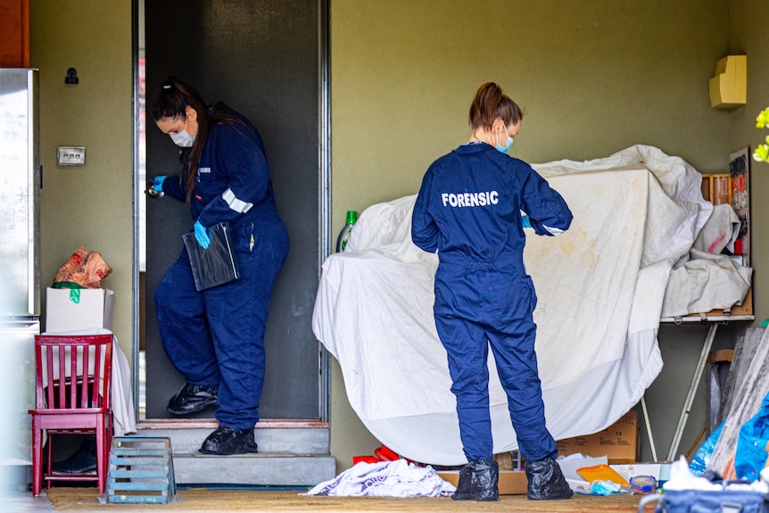 Forensic examiners in a garage, wearing protective clothing.