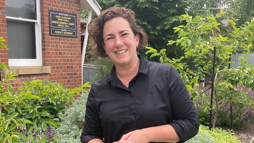 A woman stands in a garden smiling