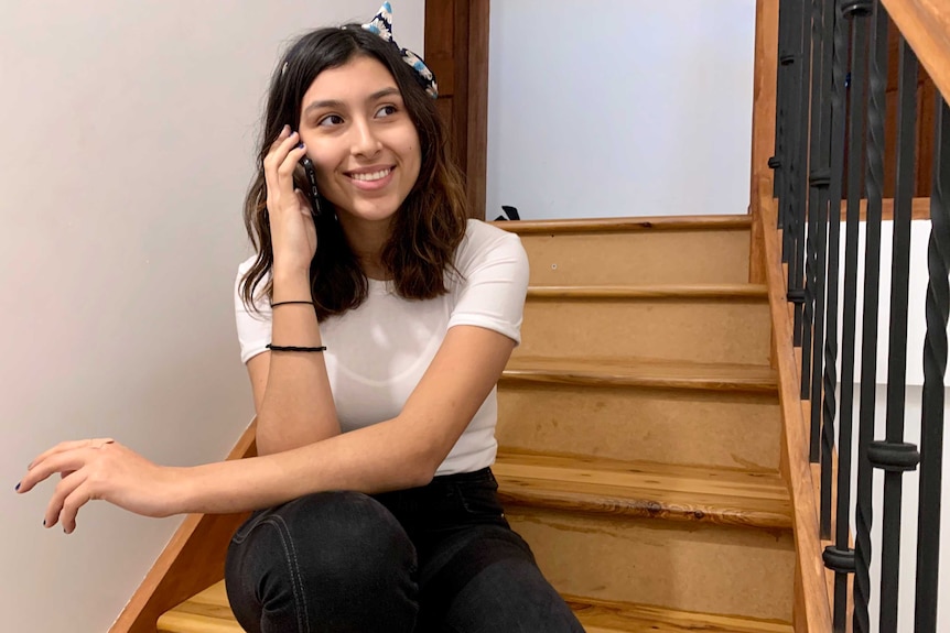 Mayela Dayeh sits on the stairs and talks on the phone.