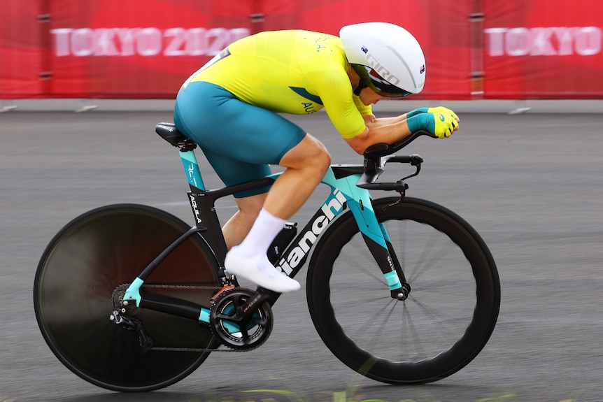 A woman wearing green and yellow lycra riding a bike