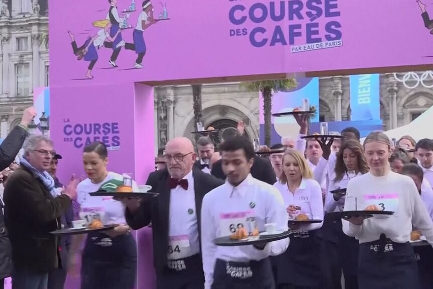 Dozens of waiters carrying trays begin a race.