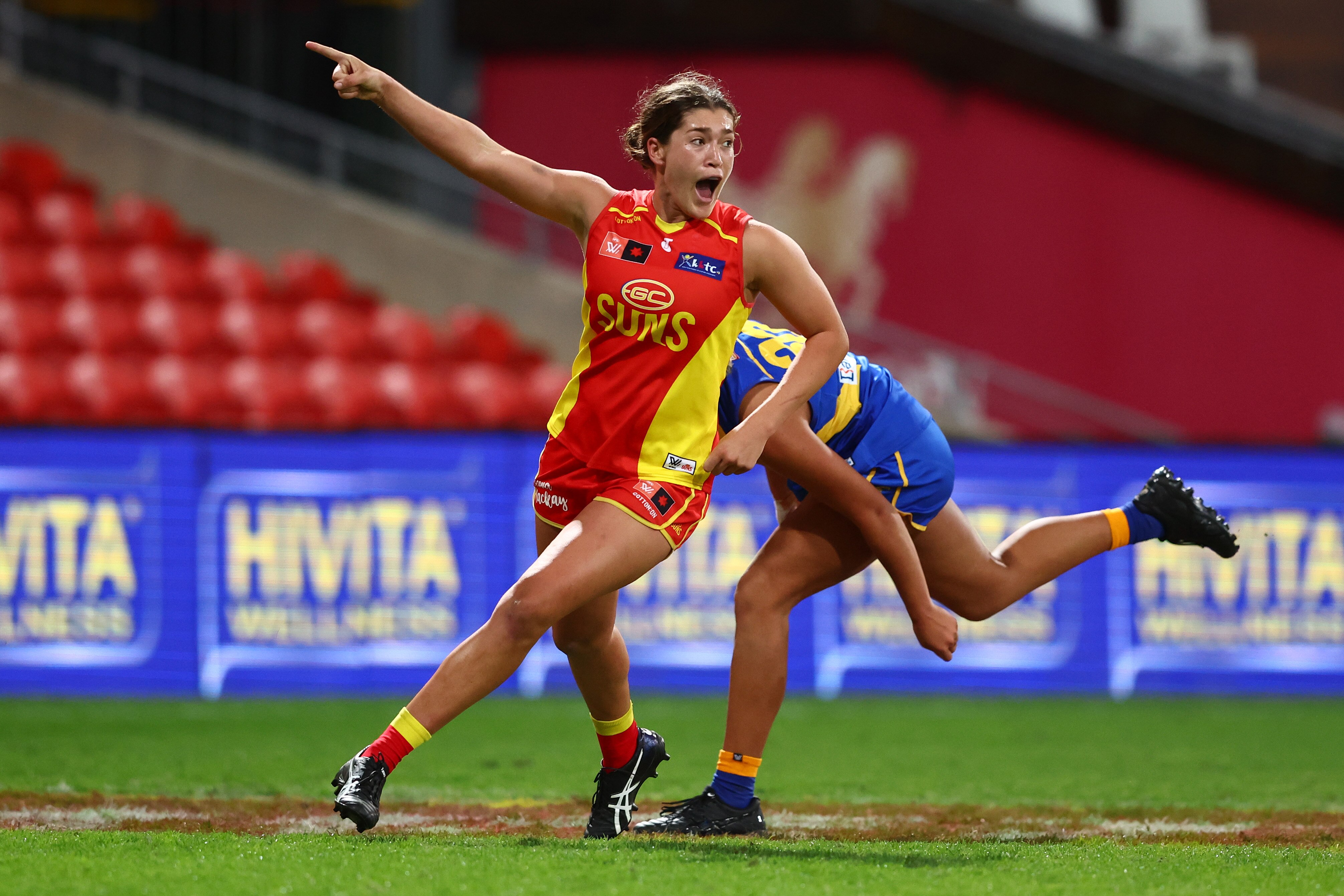 A Gold Coast Suns AFLW player points towards goals after kicking a major.