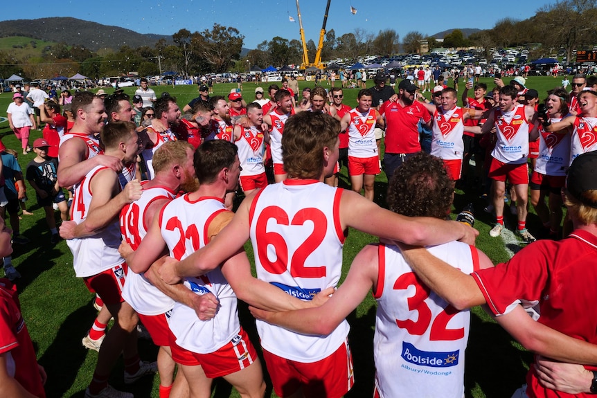 Chiltern Swans reserves players and coaches stand arm in arm in a circle to sing the club song