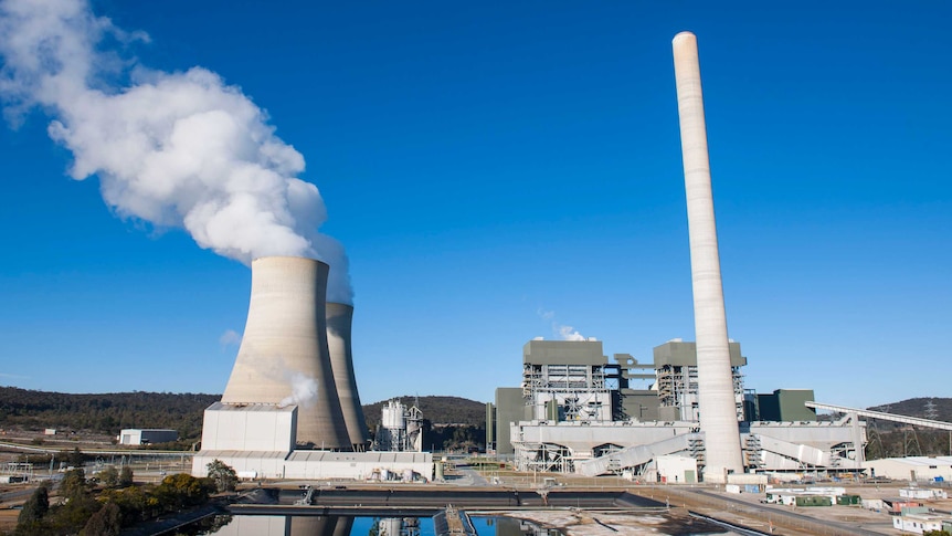 A power plant belching into a clear blue sky.