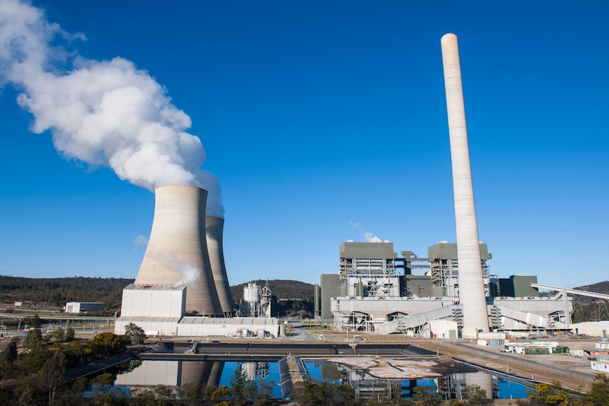 A coal power station with a large smoke stack with steam coming from it