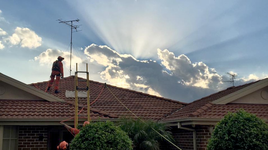 SES volunteers work to repair a roof that was damaged by a hailstorm.