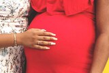 Woman puts hand on pregnant woman's belly area
