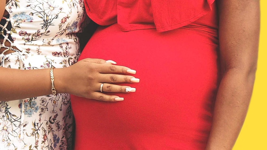 Woman puts hand on pregnant woman's belly area