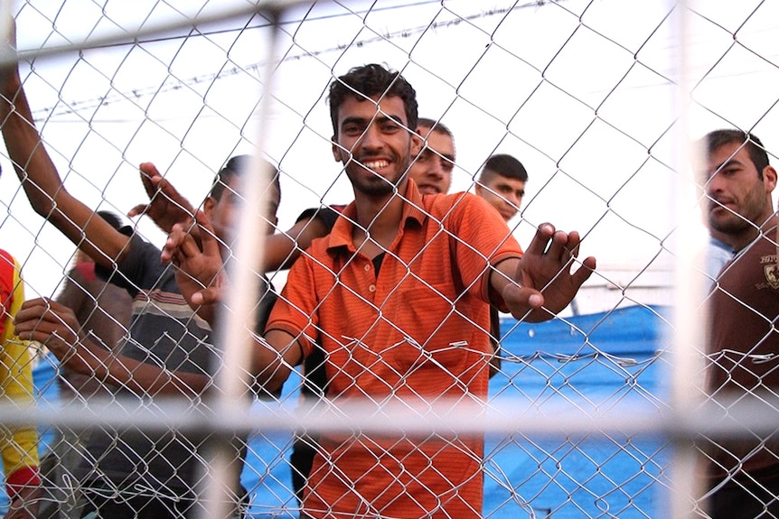 Iraq men behind a wire fence at the Debaga camp.