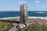 A lighthouse on a coastline covered in scaffolding works