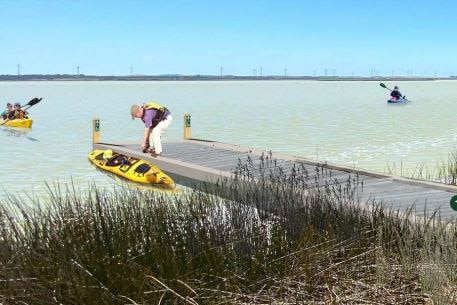 A computer graphic of people kayaking next to a small wharf