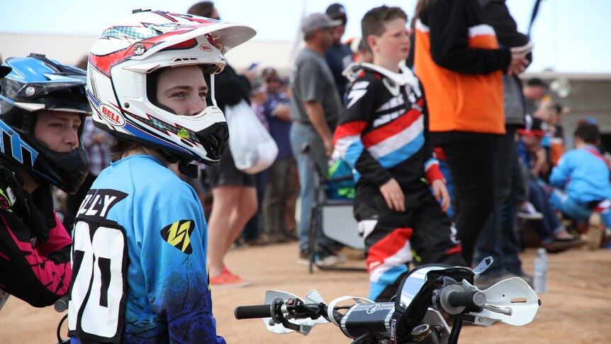 A junior motocross rider looks out over the competition track.