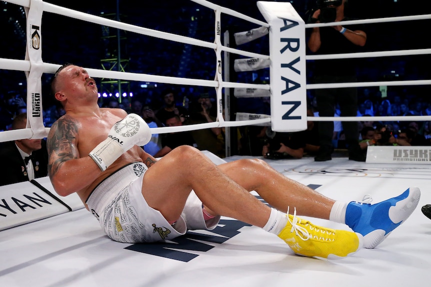A Ukrainian male boxer sits on the canvas after being knocked down.