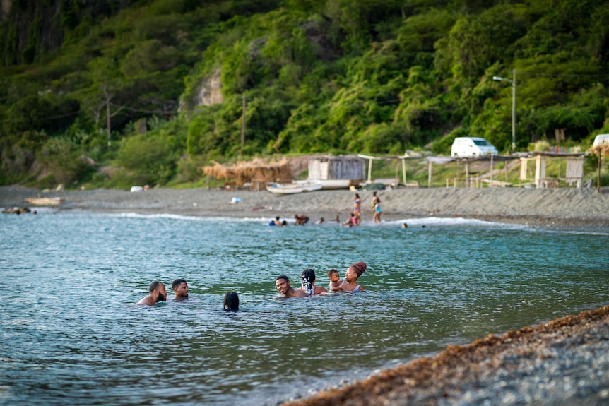 Un grupo de personas nadando en hermosas aguas azules. 