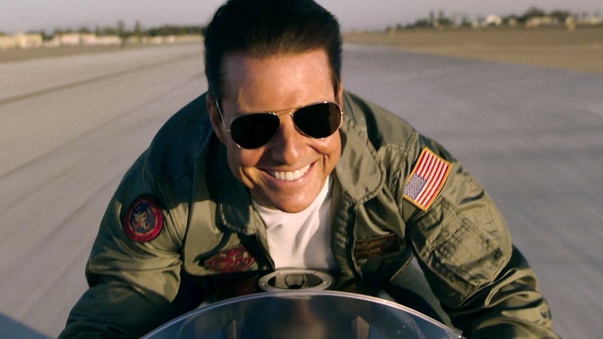Tom Cruise on a motorbike smiling