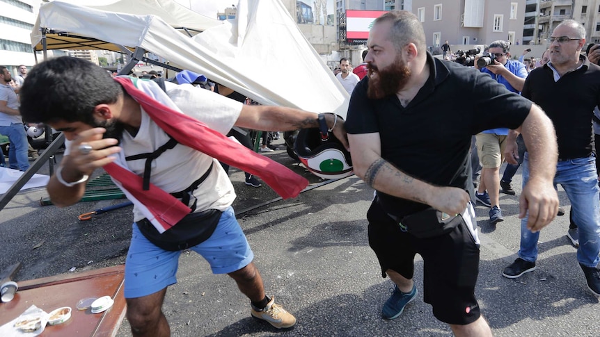 A man in black hits another man in the face.