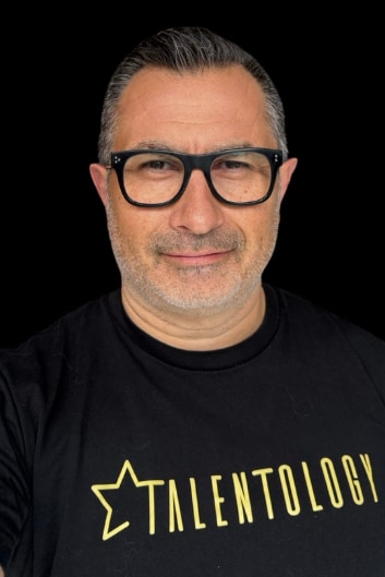 A headshot of a man with thumb-up gesture.