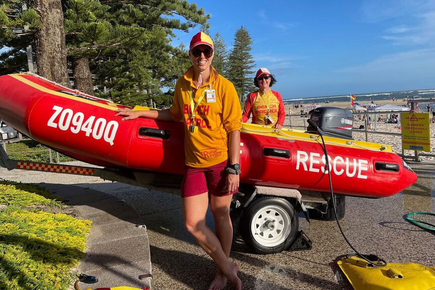 Two lifesavers standing with red rescue boat
