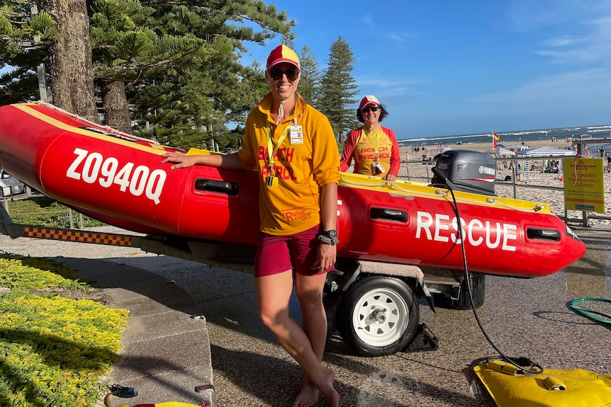 Two lifesavers standing with red rescue boat