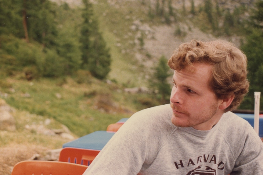 Man in grey jumper looking to the side.