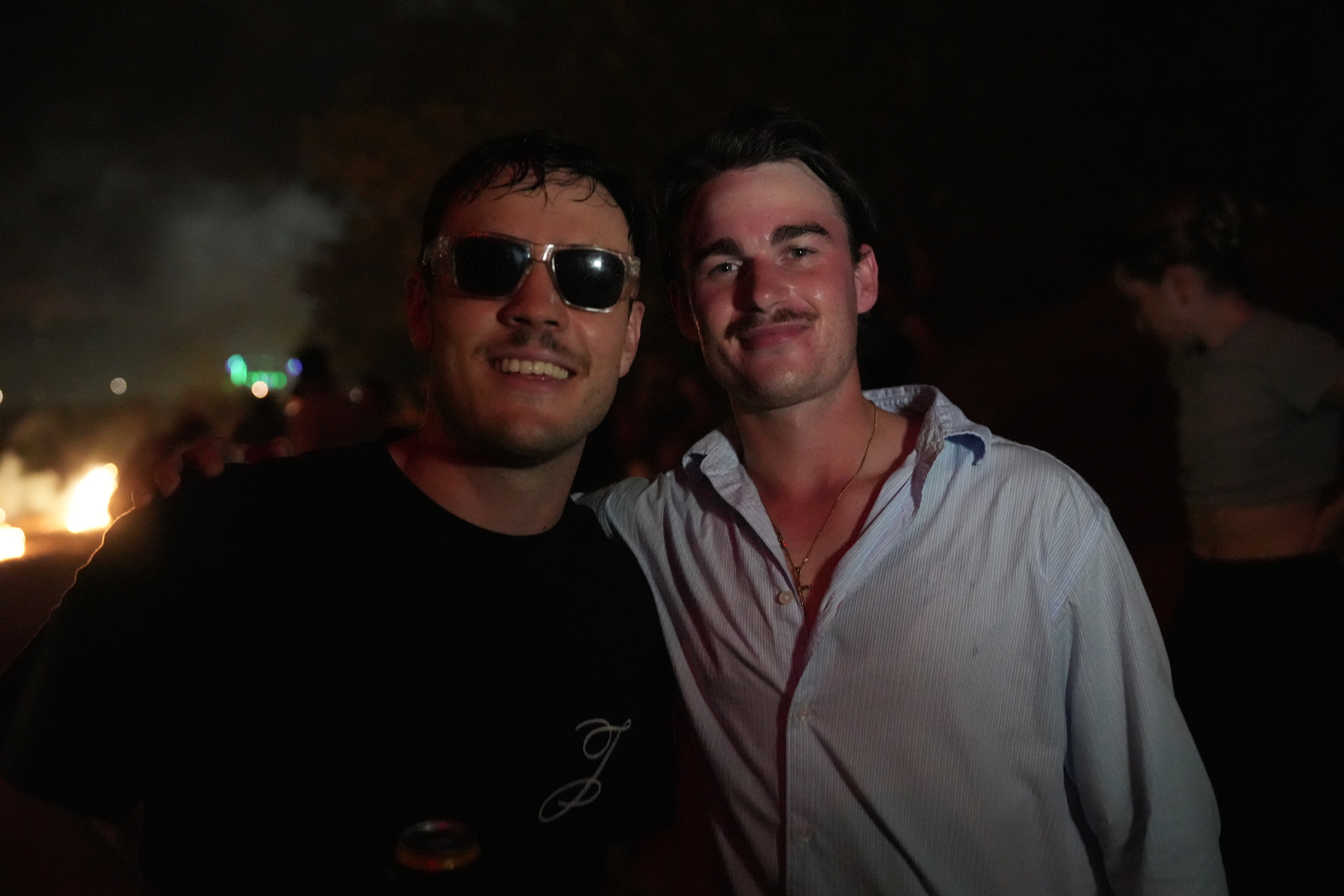 A close up of two men with some fireworks exploding over the left shoulder of the the man on the left