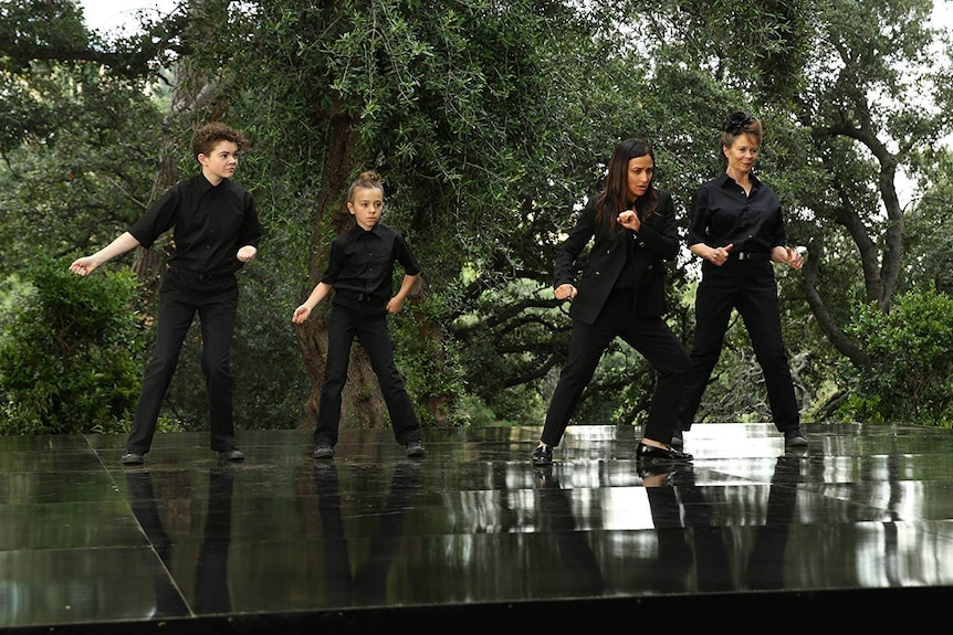 An older woman, mother and two children dancing on a stage