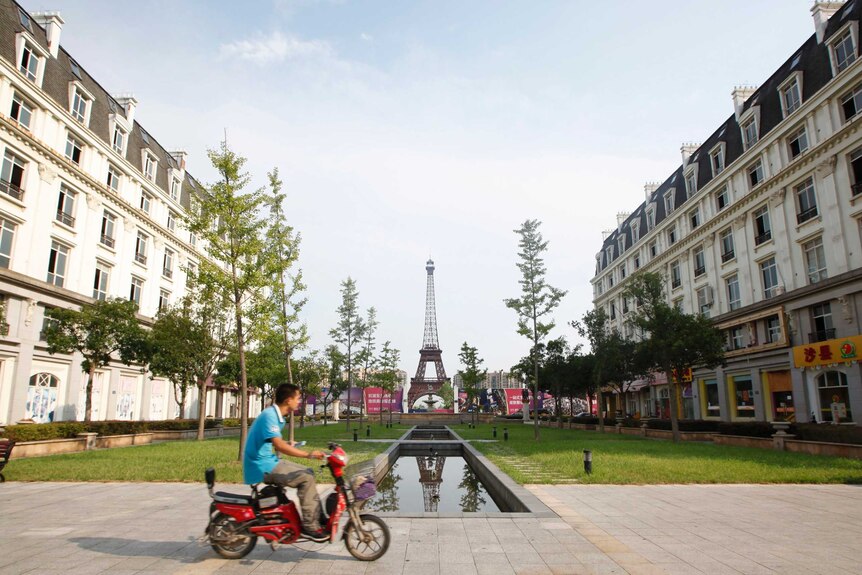 A man rides a motorcycle past a replica of the Eiffel Tower at the Tianducheng development in Hangzhou.