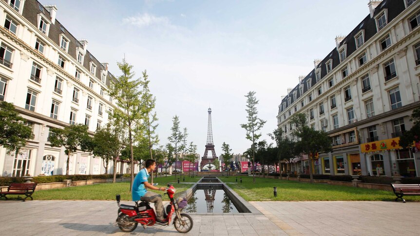 A man rides a motorcycle past a replica of the Eiffel Tower at the Tianducheng development in Hangzhou.
