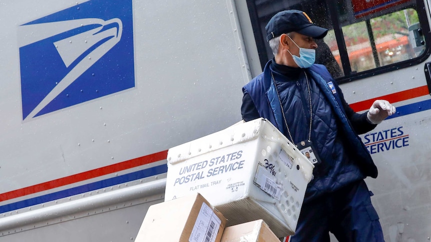 A US postal worker in a mask outside a truck